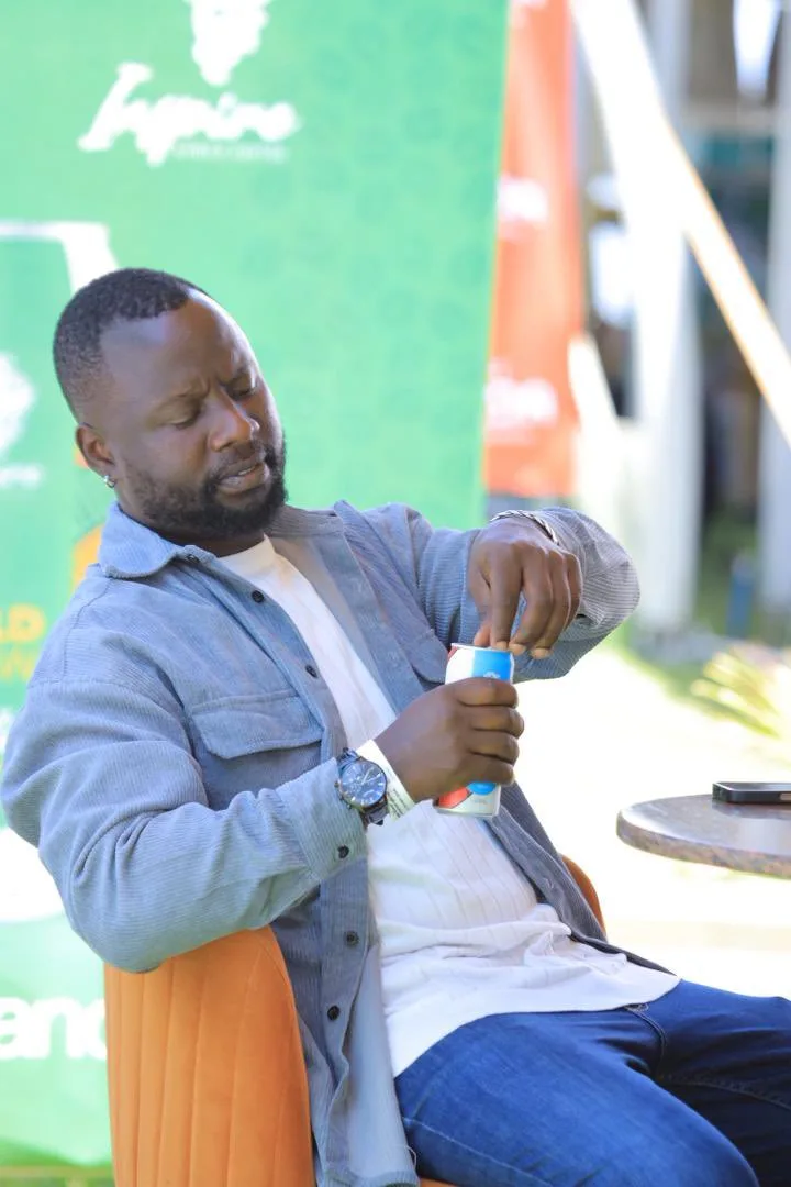 A man in a denim shirt sitting outdoors and opening a can of cold brew, in front of the green Inspire cold brew banner.