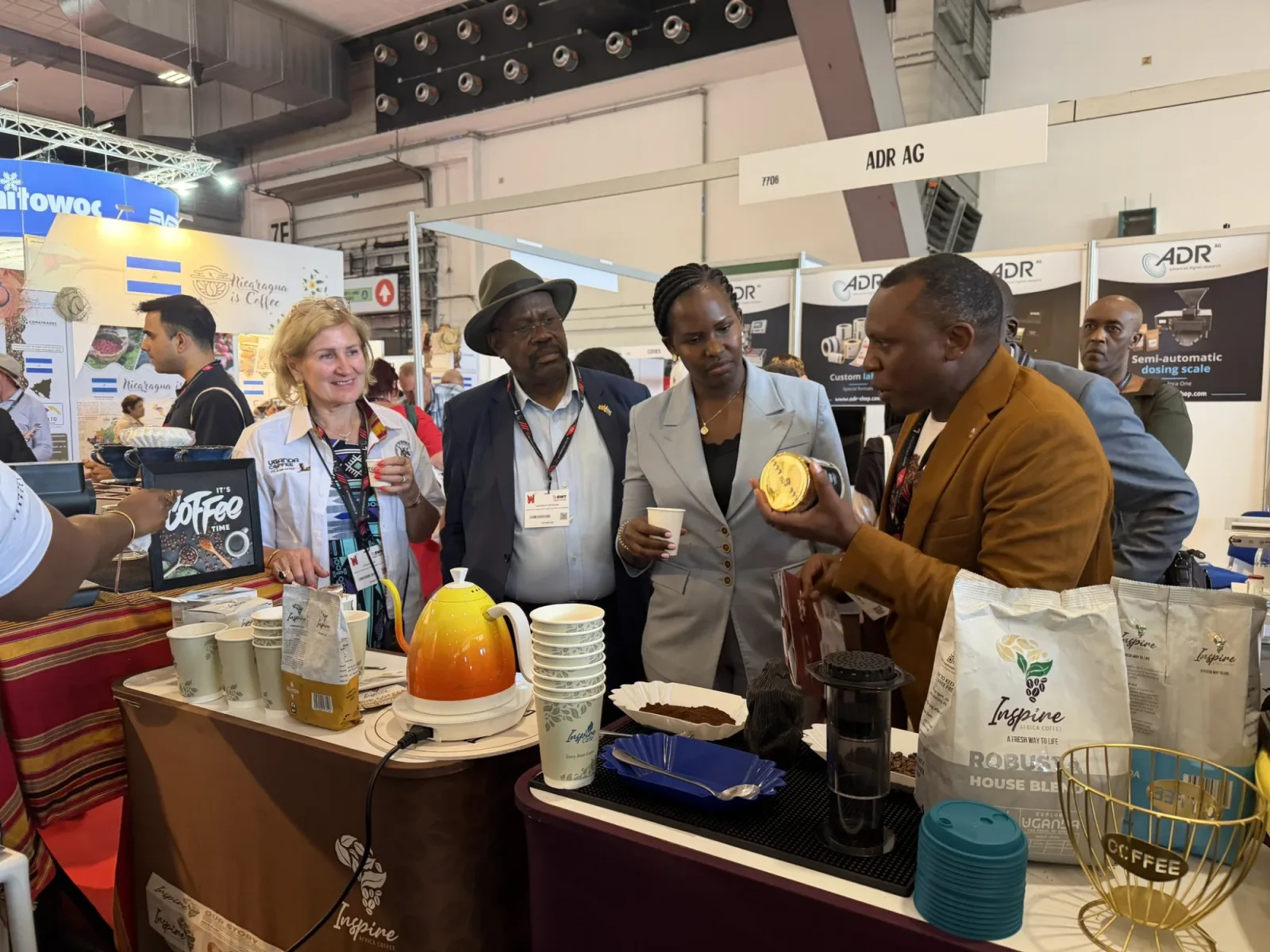 Hon. Desire Muhooza and the Uganda delegation tasting coffee at the Africa Coffee Park booth, World of Coffee Brussels.