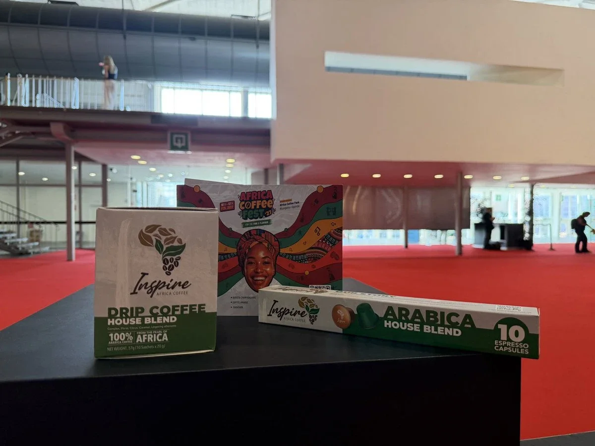 Inspire Africa Drip Coffee House Blend, Arabica espresso capsules and an Africa Coffee Fest 2027 flyer on a plinth at World of Coffee Brussels.
