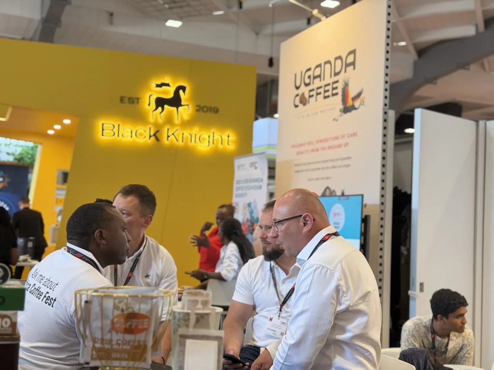 Buyers in conversation in front of the Uganda Coffee stand at World of Coffee Brussels